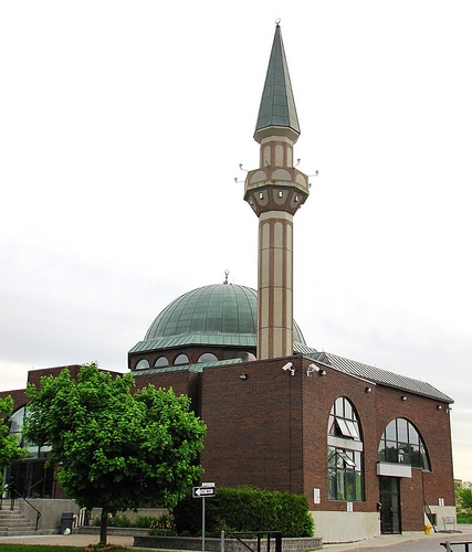 Exterior view of a building with distinct architectural design, including a raised minaret and central dome.